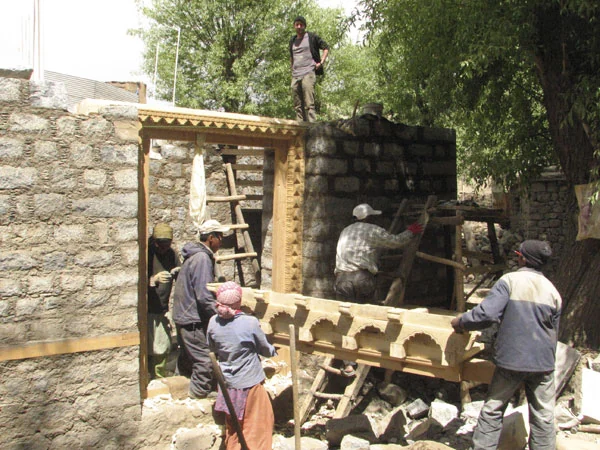 Fixing the carved timber shing-tsak over the main entrance