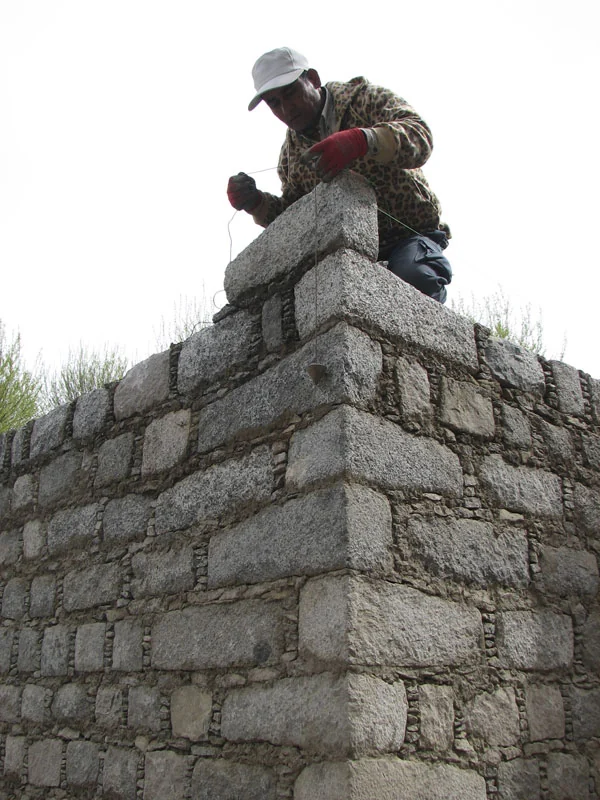 A mason laying dressed stone on the Tibetan-style walls